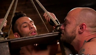 Suspended bdsm sub caged for cock tugging