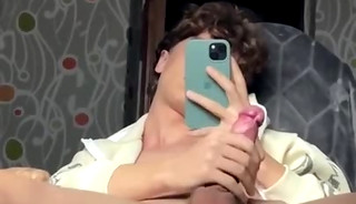 A handsome curly-haired young man masturbating in front of a mirror.